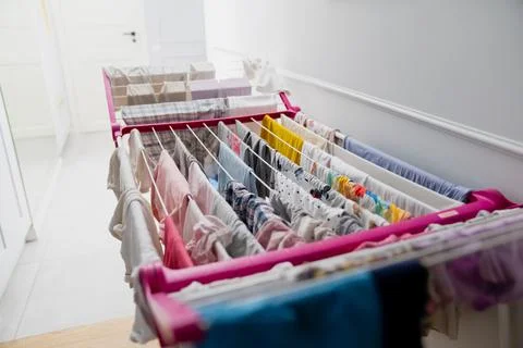 Laundry hangs from an indoor drying rack in a side-facing composition Stock Photos