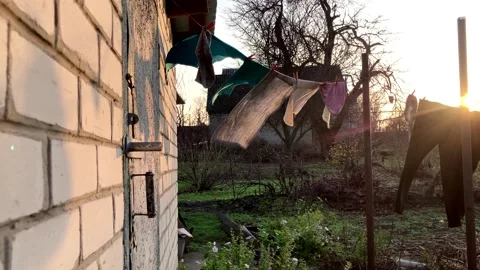 Laundry hangs out to dry on a line in the wind in a village courtyard at sunset Stock Footage 339179728