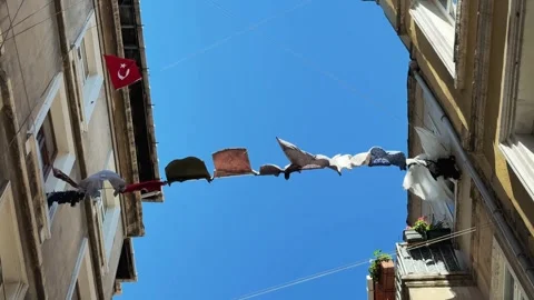 Laundry lines and Turkish flag hanging between tall buildings in narrow old Vidéo 321347732