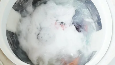 Laundry machine drum filling with bubbling water and dense white foam while Stock Footage 335644049