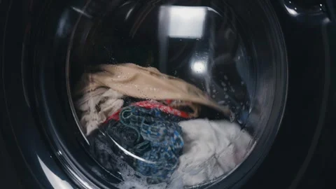 Laundry machine drum washing colorful clothes, spinning vigorously with water Stock Footage 344912112