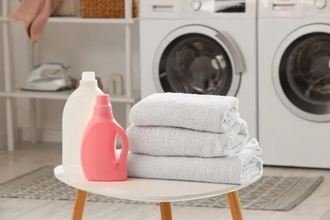 Laundry room essentials with detergent bottles, fabric softener, and stacked  Stock Photos