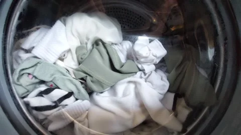 Laundry spinning inside a washing machine, close-up view through the glass door. Stock Footage 335834118