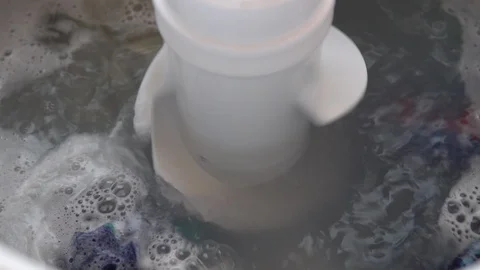 Laundry washing machine in action agitating dirty clothes in soapy water. Stock Footage 92859873