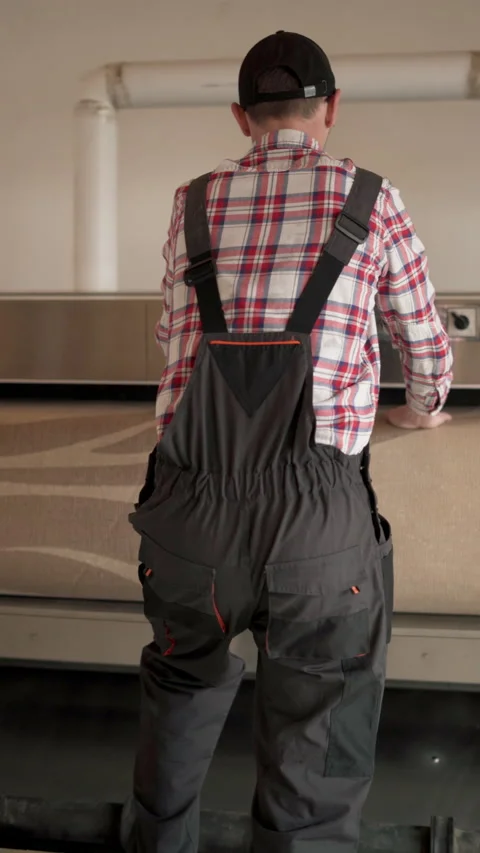 Laundry worker in cap and overalls in the process of working on automatic Stock Footage 269695015