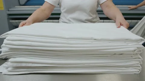 A laundry worker puts clean bed linen in a pile Stock Footage 223158343