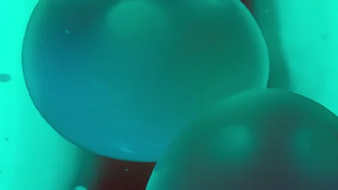 Lava bubbles floating in dark liquid under green light Stock Footage 293249417