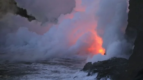 Lava flows after sunset into the ocean, steam cloud rising from water surface