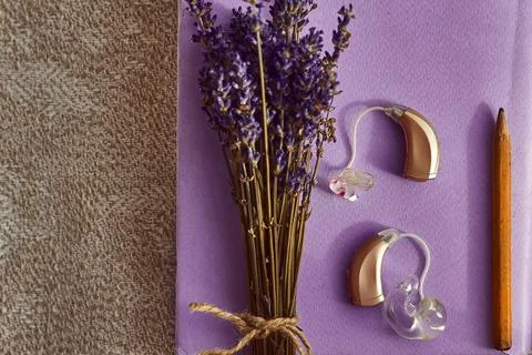 Lavender blooms complementing advanced hearing aids and a pencil, representin Stockfoto's