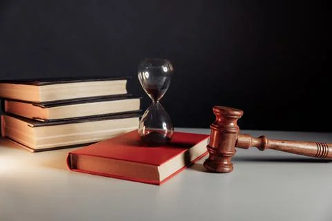 Law code. Hourglass on red book and judge gavel Stock Photos
