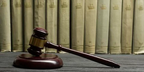 Law concept - Open law book with a wooden judges gavel on table in a courtroom 库存照片