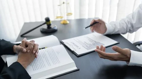 Law,libra scale and hammer on the table, 2 lawyers are discussing about contr Stock Photos