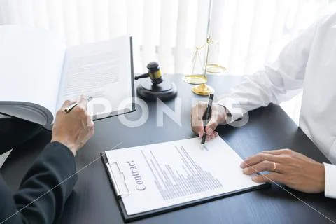 Law,libra scale and hammer on the table, 2 men are dealing and signing ...