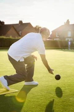 A lawn bowls player standing on a small yellow mat preparing to deliver a bowl Stock Photos