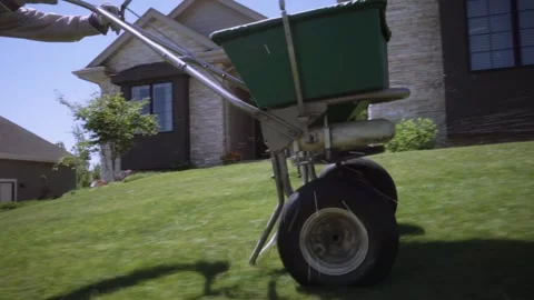 Lawn care worker using a Green Push Fertilizer Spreader Stock-Footage 255658511