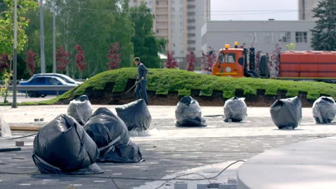 Lawn laying preparation by soil raking performed by city worker Stock Footage 244635291