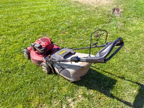 Lawn mower on grass in a backyard during daytime under clear sky Stock Photos