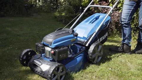 Lawn mower is started and then begins cutting grass moving out of shot Stock Footage 111397354