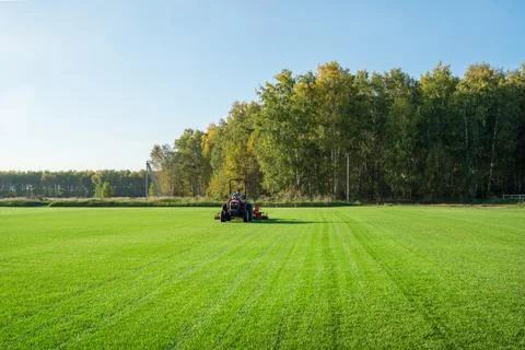 Lawn mower tractor effectively cutting off the tall grasses in the lawn. The Stock Photos