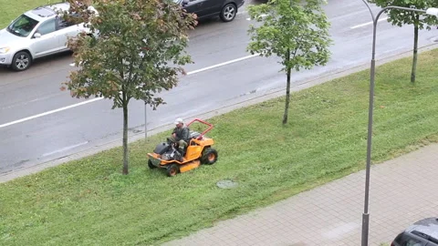 Lawn mowing. A worker driving a self-propelled mower. Mows the grass on the s Stock Footage 138139985