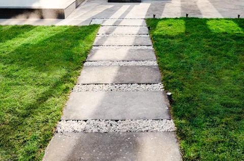 Lawn with paved garden path. Simple paths with grass field. Stock Photos