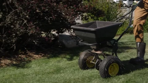 Lawn technician using a push spreader Stockbeeldmateriaal 139148899