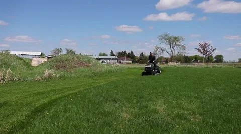 Lawn tractor driver cutting nice green lawn Stock Footage 50064007