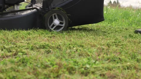 A lawnmower seen from the side as it drives over the grass. Video stock 317677820