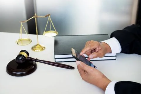 Lawyer hand using smart phone in court (justice, law) with sounding block. Foto stock