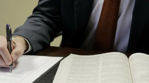 Lawyer writes down notes while reading text Stock Footage 59803413