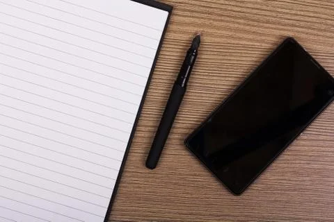 Lay flat image of a notebook and phone on a wooden surface Stock Photos