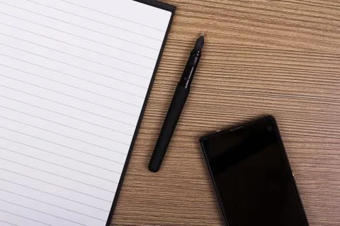 Lay flat image of a notebook and phone on a wooden surface Stock Photos