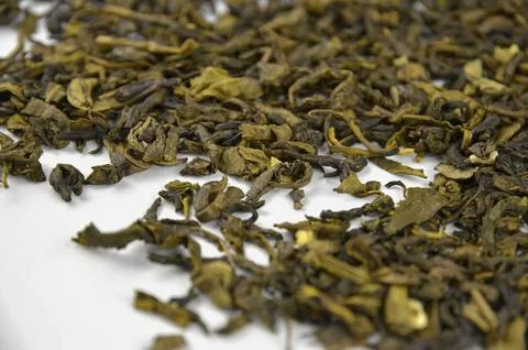 Layer of dry green leaf tea on a white background, closeup (macro), side view Stock Photos