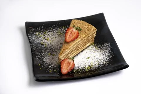 Layer sponge cake  with strawberries on a black plate isolated on white backg Stock Photos