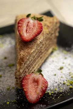 Layer sponge cake with strawberries on a black plate on wooden background Stock Photos