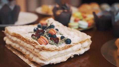 Layered cake decorated with berries, mint and candy on table with sweets Video stock 77160631