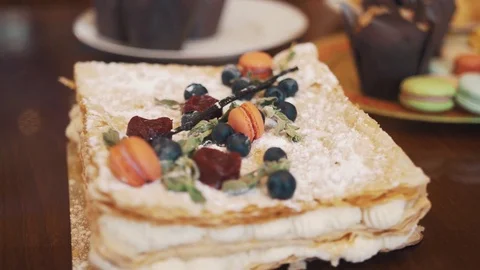 Layered cake decorated with berries, mint and candy on table with confectionery Video stock 77160677
