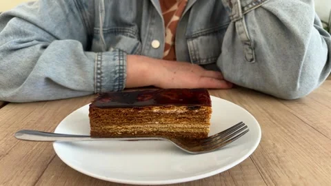 Layered cake slice with caramel glaze on white plate, wooden table Video stock 343408778