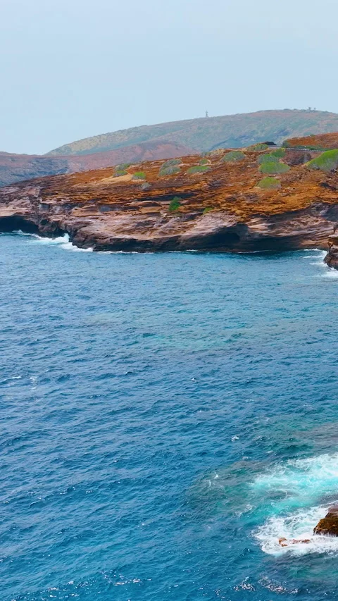 Layered cliffs with crashing waves and rolling hills. Vertical video. Video stock 319760005
