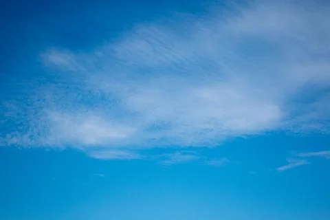 Layered clouds against the background of a bright blue sky in clear weather Stock Photos