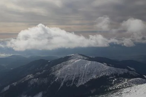 Layered Clouds Rolling Over Forested Mountain Peak at Dusk 库存照片