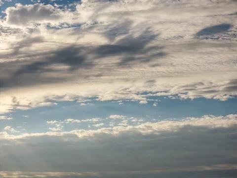 Layered cloudscape with soft gray and white cloud bands stretching across a pale 스톡 사진