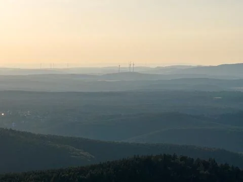 Layered Forest Hills at Sunset With Wind Turbines on the Horizon and Soft H.. Stock Photos