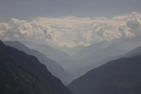 Layered mountain range silhouettes with clouds and morning haze Stock Photos