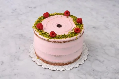 Layered Raspberry Pistachio Cake round frosted with light pink cream and ga.. Foto stock