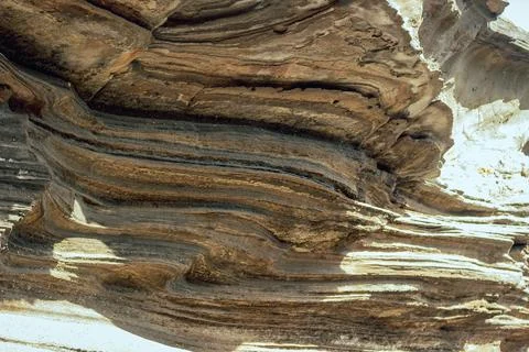 Layered rock formations with erosion patterns and sunlight reflections Stock Photos
