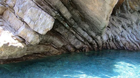 Layered rocks and bright clear sea water in cave Stock Footage 124127344