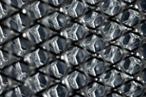 Layered silver metallic mesh in macro view with dark geometric pattern and .. Photos