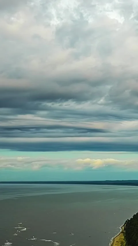 Layered storm clouds drifting above calm sea coastline timelapse Stock Footage 340429240