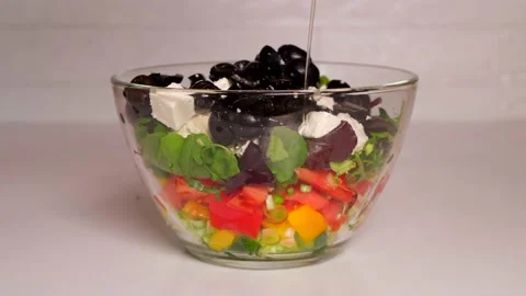 Layered vegetable salad in a transparent bowl, seasoned with olive oil Stock Footage 154241978